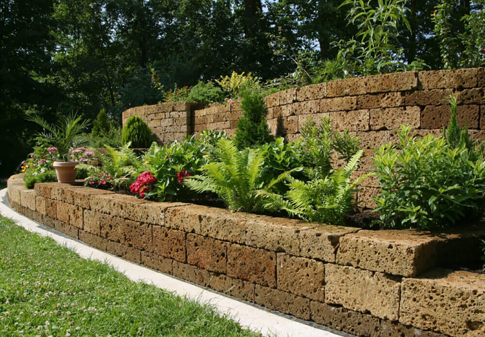 Bushes line the raised garden bed against the stone wall