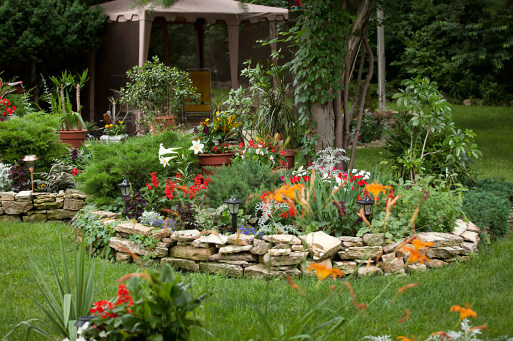 The stacked stone wall adds a rustic, homey quality to the landscaping