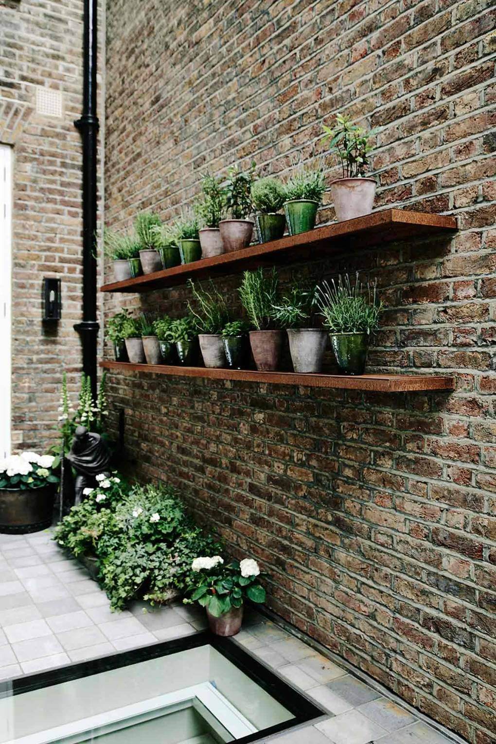 The garden terrace with potted herbs on rusted shelves