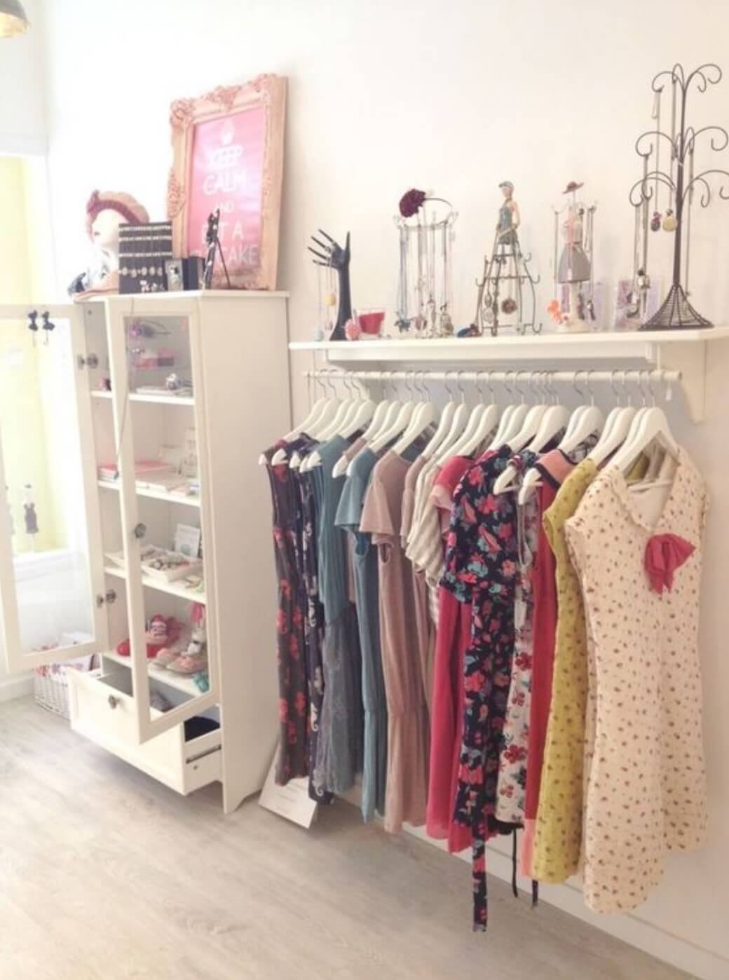 Wardrobe made with a wooden shelf and a low tube fixing to the wall with hanging dresses.