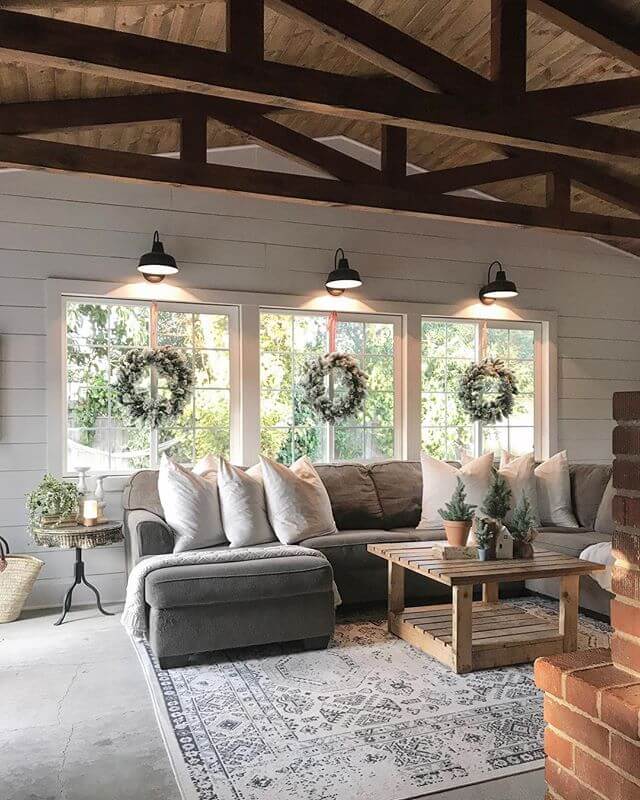 Large room with exposed beams, the windows with light fixtures and wreaths