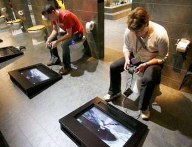 men sitting in the toilet and on the floor a screen with controls to play video games