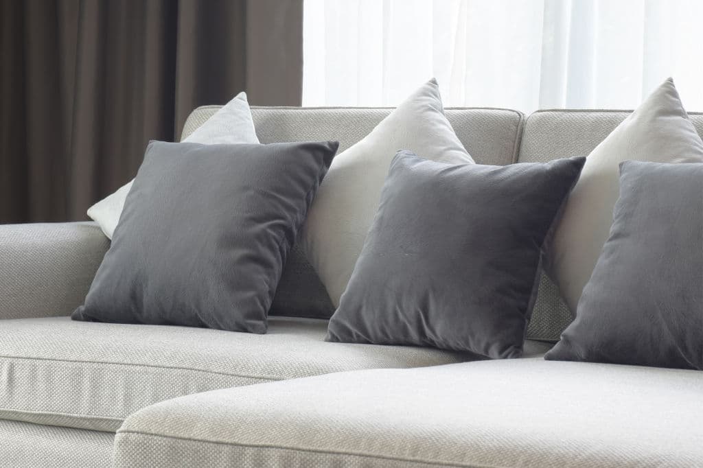 9 white and gray pillows setting on beige couch