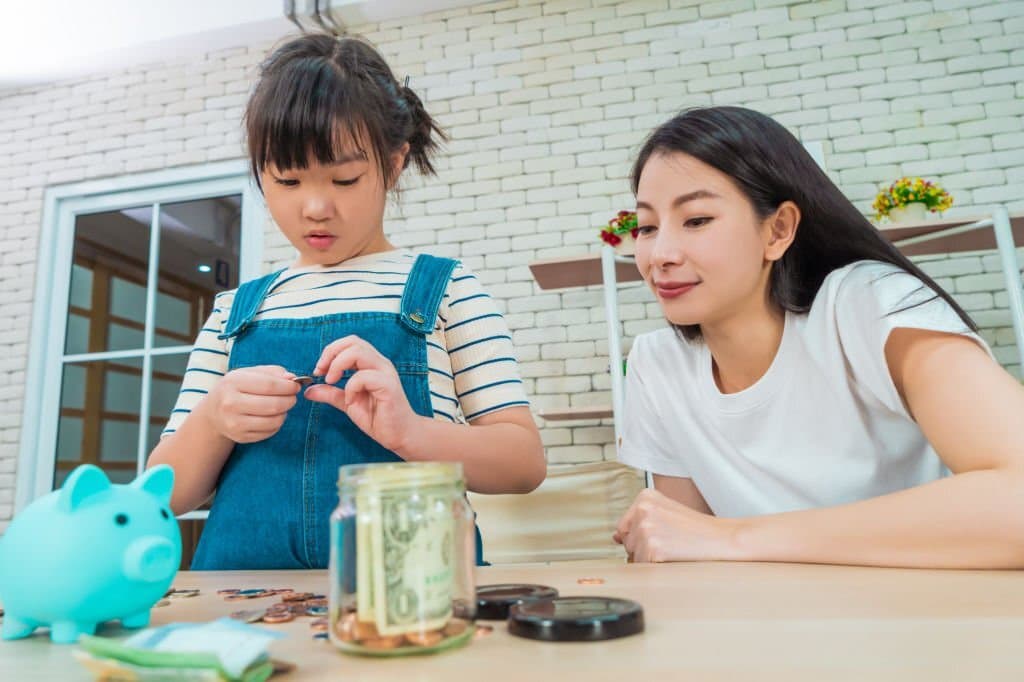 mother is teaching daugther on financial saving