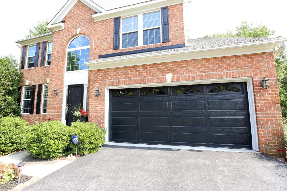 black garage door with red brick house